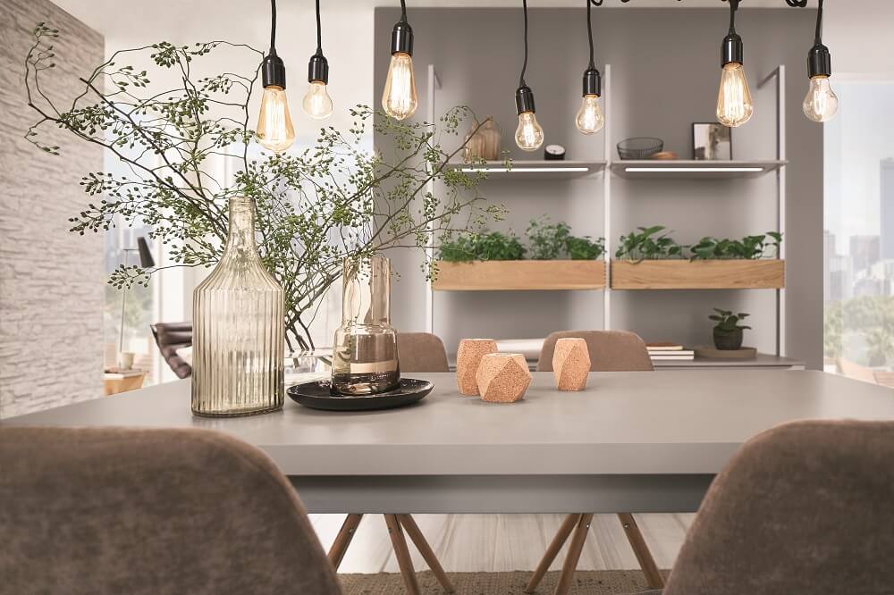 Dining table with pendant lights and plants.
