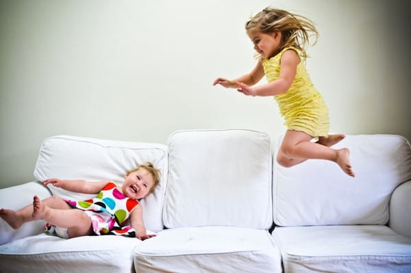 2 girls jumping on white sofa