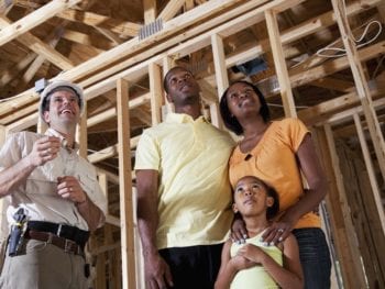 African American family standing in house under construction talking with builder.
