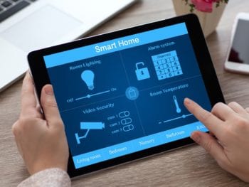 woman hands holding tablet PC computer with smart home near laptop and phone