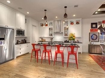 White kitchen with red stools.
