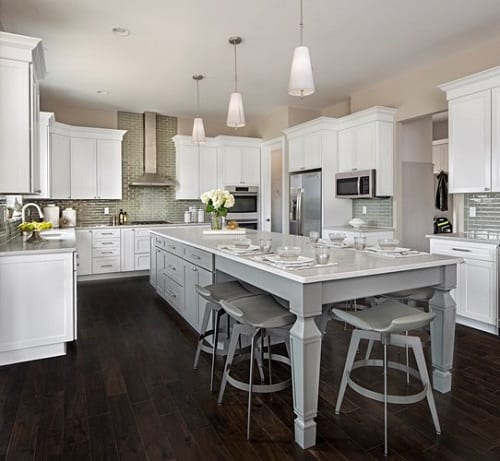 Kitchen with large island with gray cabinets surrounded by white cabinets.
