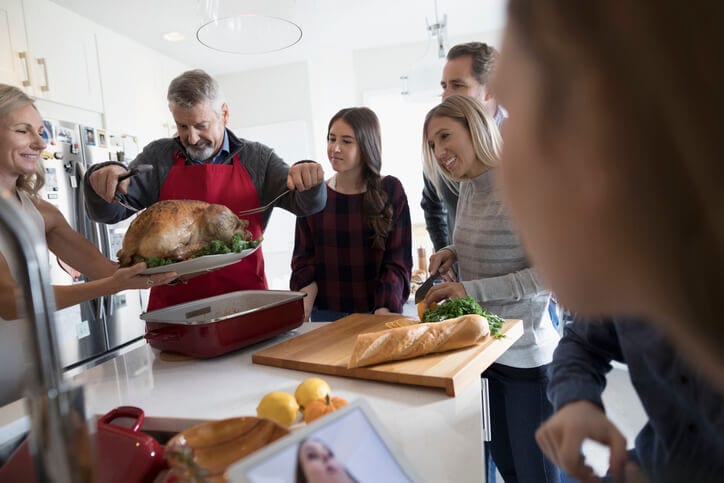 Family in the kitchen pulling out a turkey.