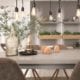 Dining table with pendant lights and plants.