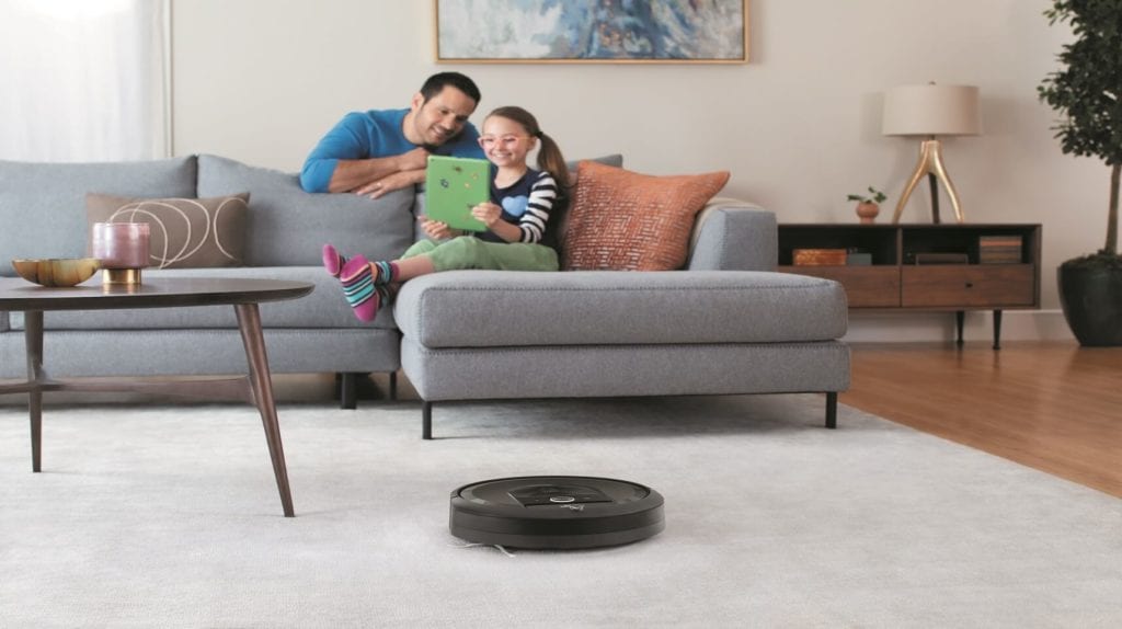 Dad with his girl looking at a smart device with a roomba.
