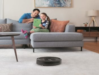 Dad with his girl looking at a smart device with a roomba.