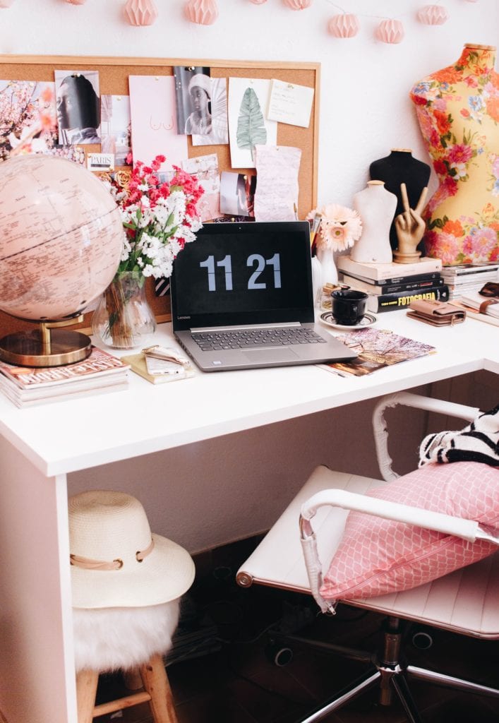 Desk with globe, laptop with pink tones.
