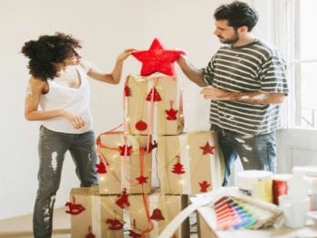 Young couple decorating a box Christmas tree.
